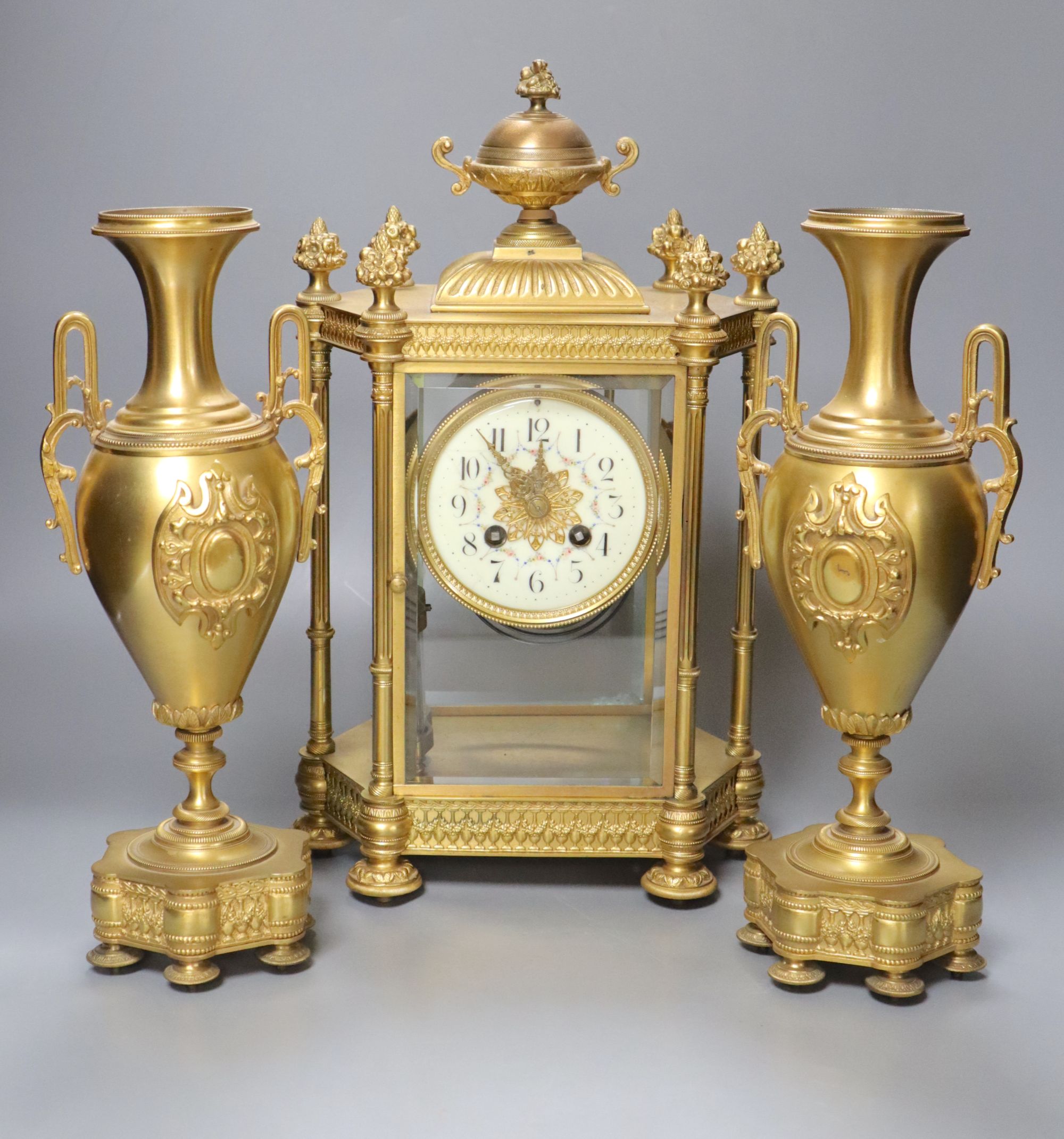 A late 19th century French garniture de cheminée comprising a four-glass mantel clock and a pair of vases